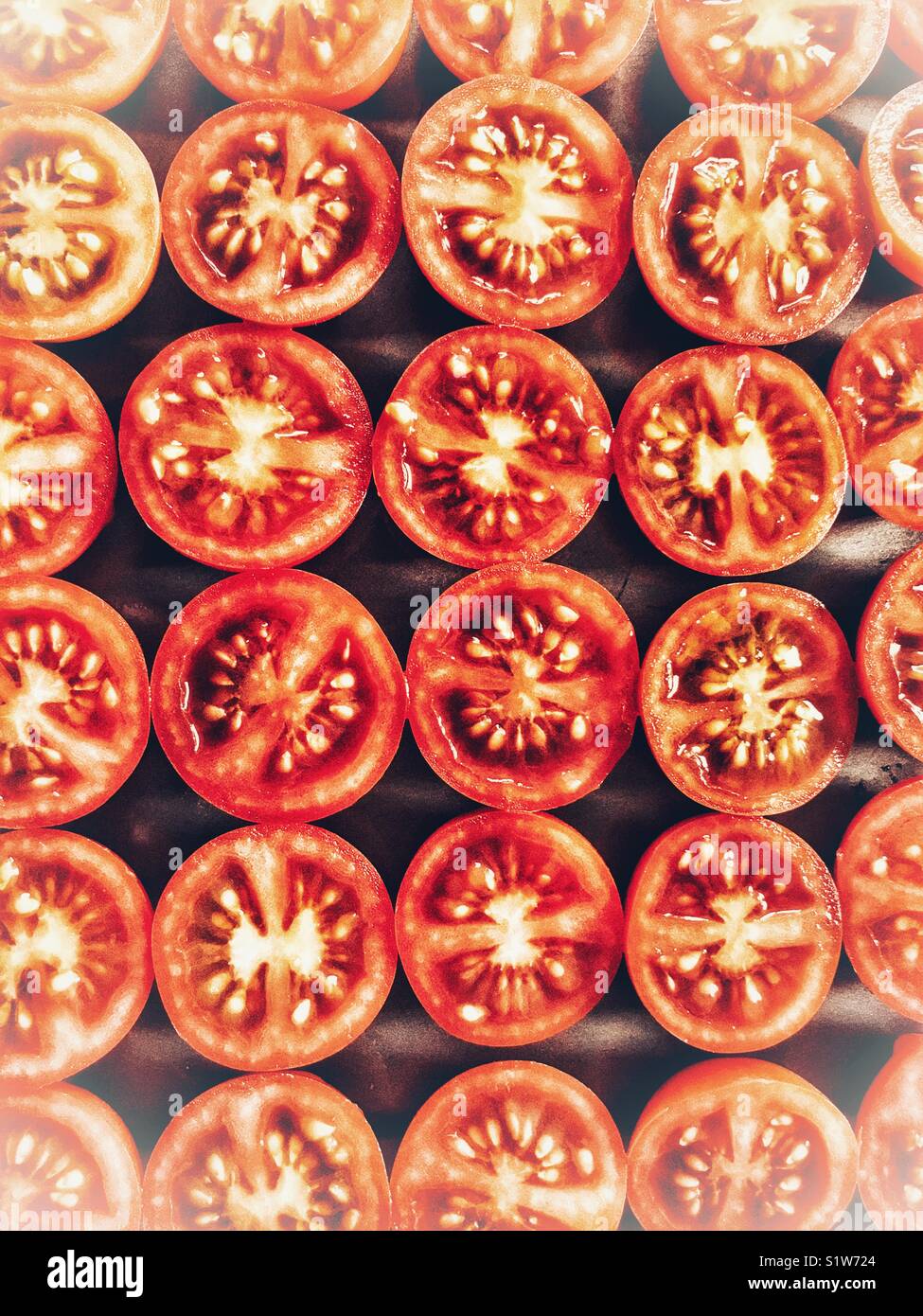 Cherry tomatoes, cut in half, on a baking tray ready to go in the oven to be roasted - Smartphone Captured Stock Image
