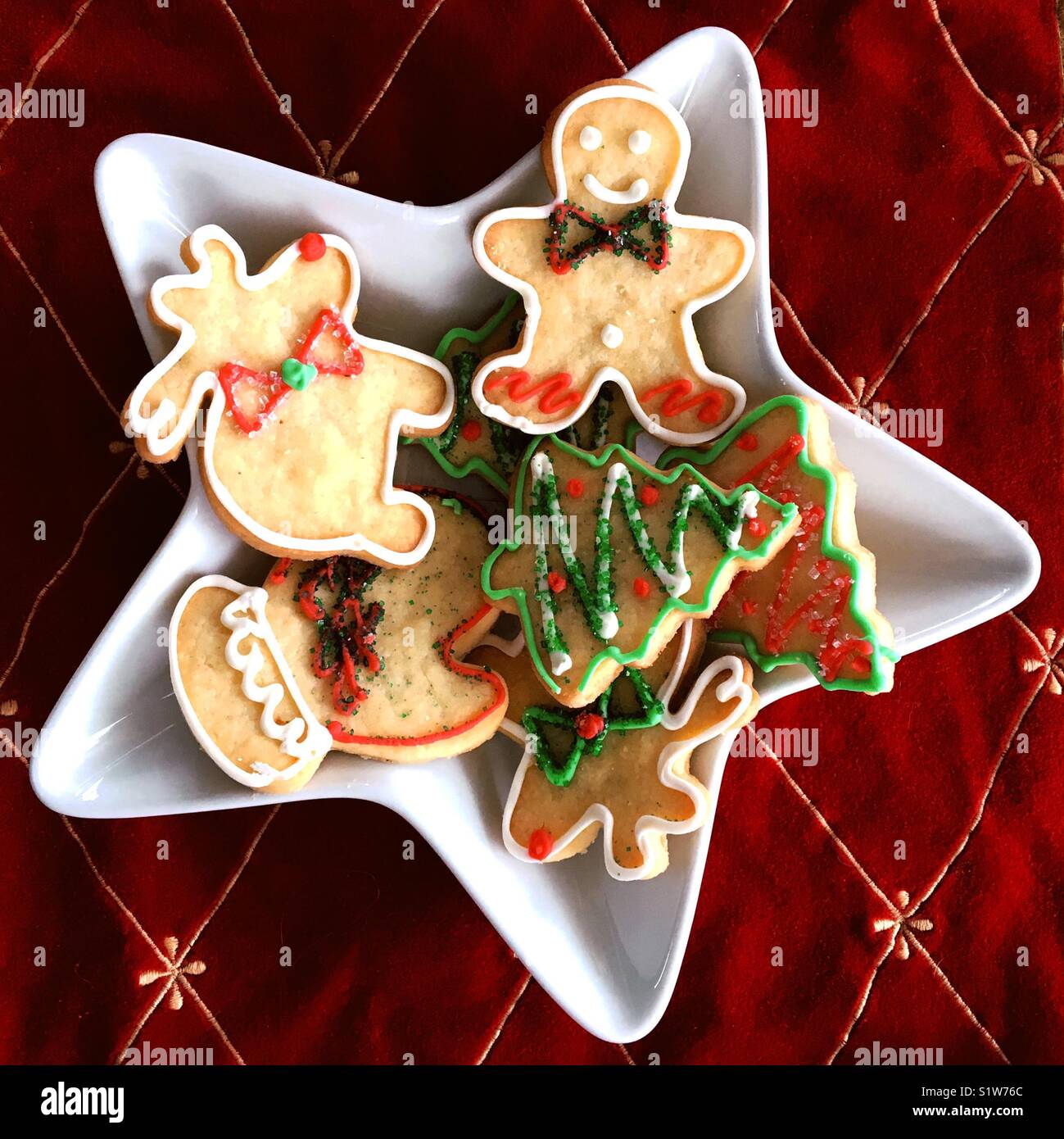 Assortment of Christmas sugar cookies on a white star shaped platter with red background   Square crop. - Smartphone Captured Stock Image