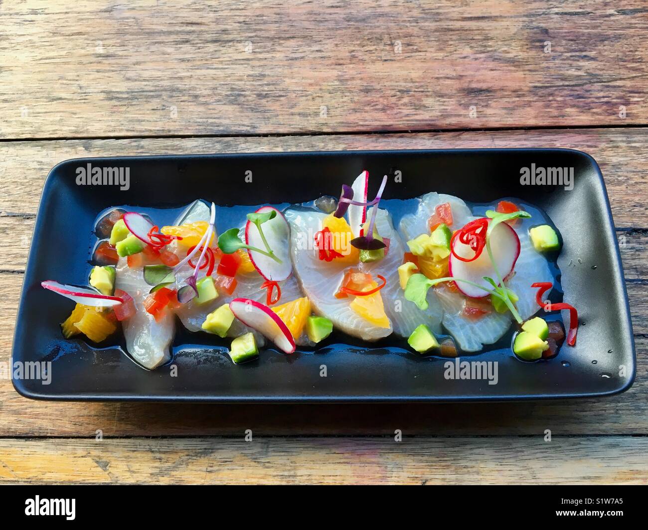 Pretty plate of cervice fish with radishes avocado mango and watercress - Smartphone Captured Stock Image