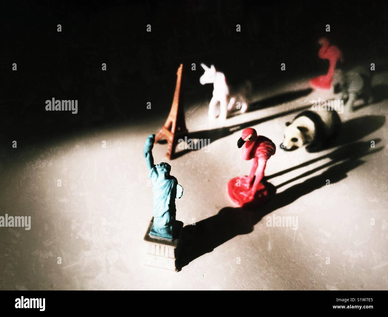 Tiny sculpture of Statue of Liberty , Eiffel Tower, flamingo, panda and unicorn with long shadows - Smartphone Captured Stock Image