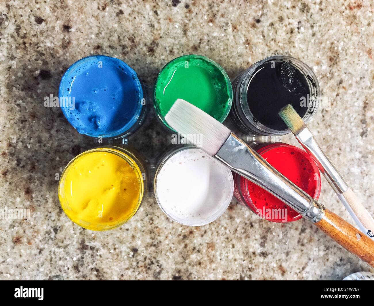 Open containers with paints and brushes on granite countertop, top view Stock Photo