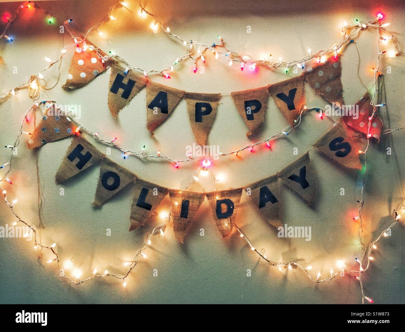 Happy Holidays banner on the wall surrounded by colorful string lights - Smartphone Captured Stock Image