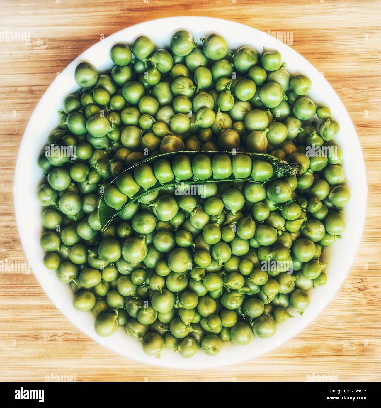 Bowl of fresh garden peas, and peas in a pod, high angle view Stock Photo