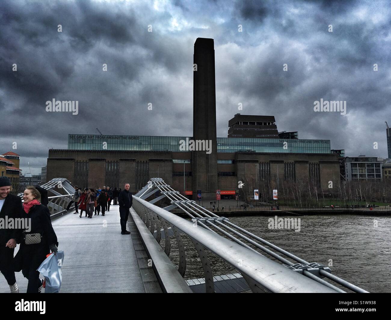 People walk across Millennium bridge by Tate Modern in London on January 1 2018 - Smartphone Captured Stock Image