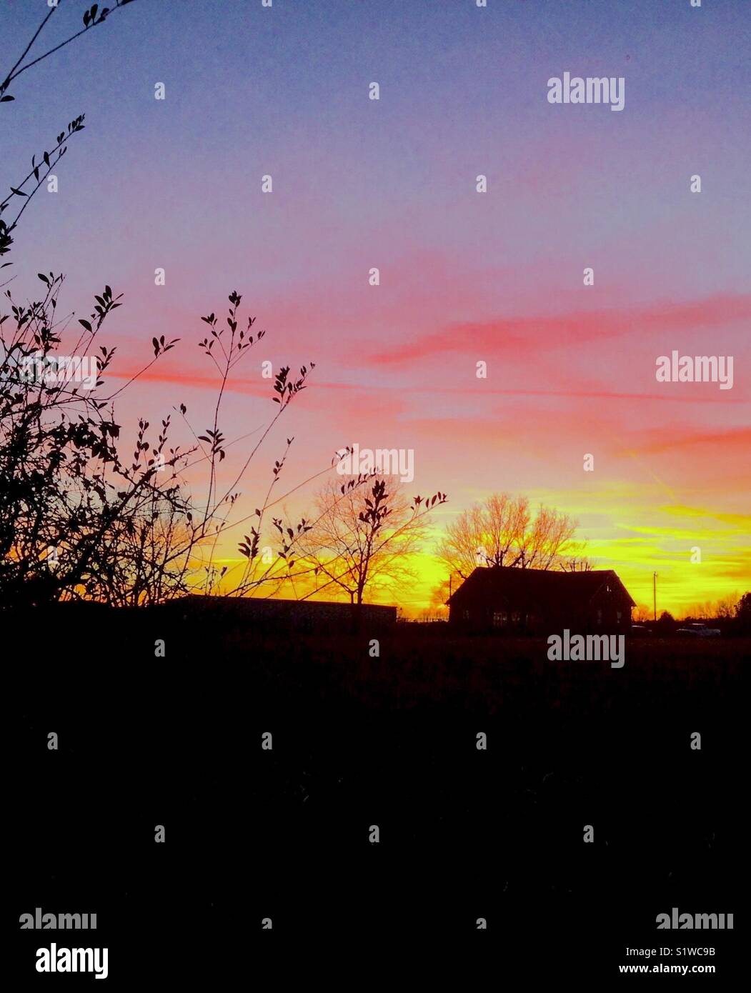 Glowing sunset with farmhouse silhouette in North Carolina - Smartphone Captured Stock Image