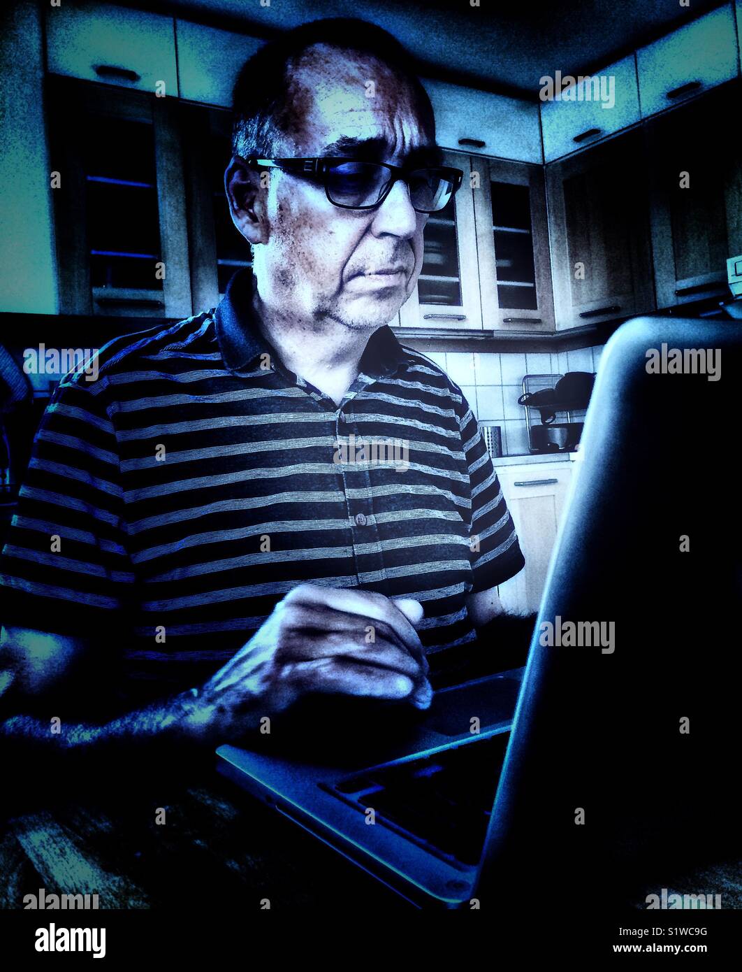 Serious middle aged man on laptop in kitchen at home, Sweden - Smartphone Captured Stock Image