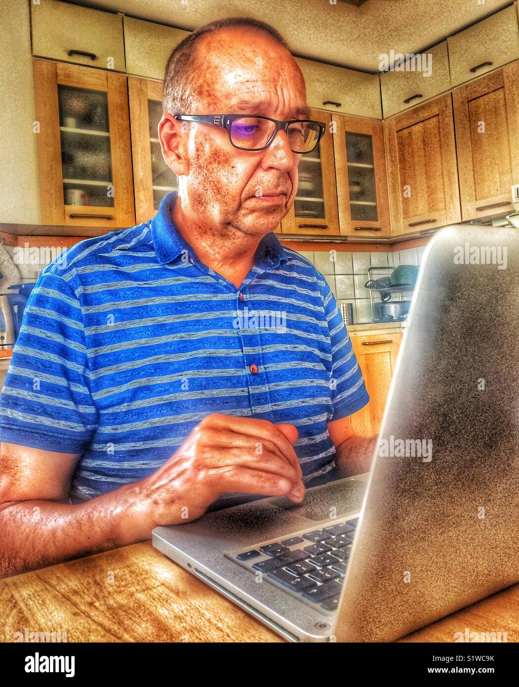 Unhappy serious man working on laptop in kitchen at home, Sweden - Smartphone Captured Stock Image