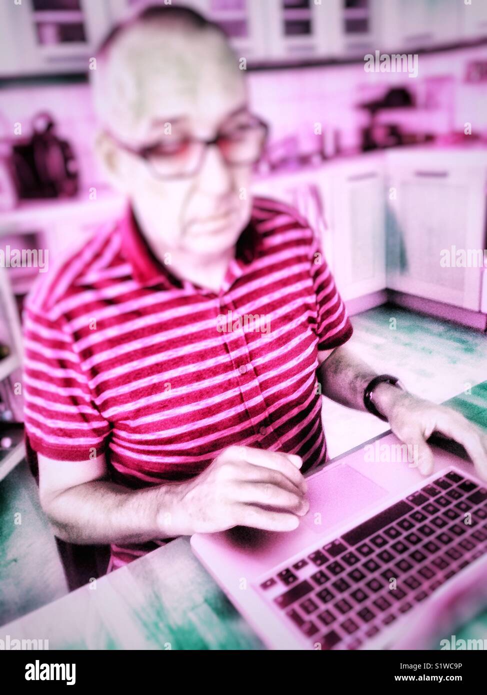 Unhappy serious man working on laptop in kitchen at home, Sweden - Smartphone Captured Stock Image