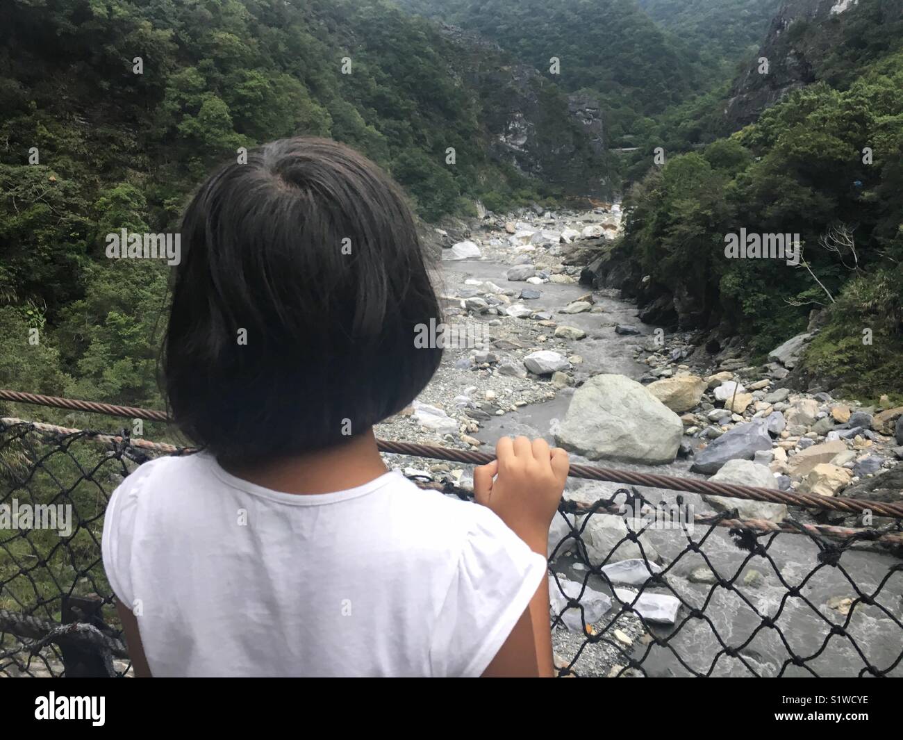 Little girl enjoying the view of a gorge from a bridge Stock Photo