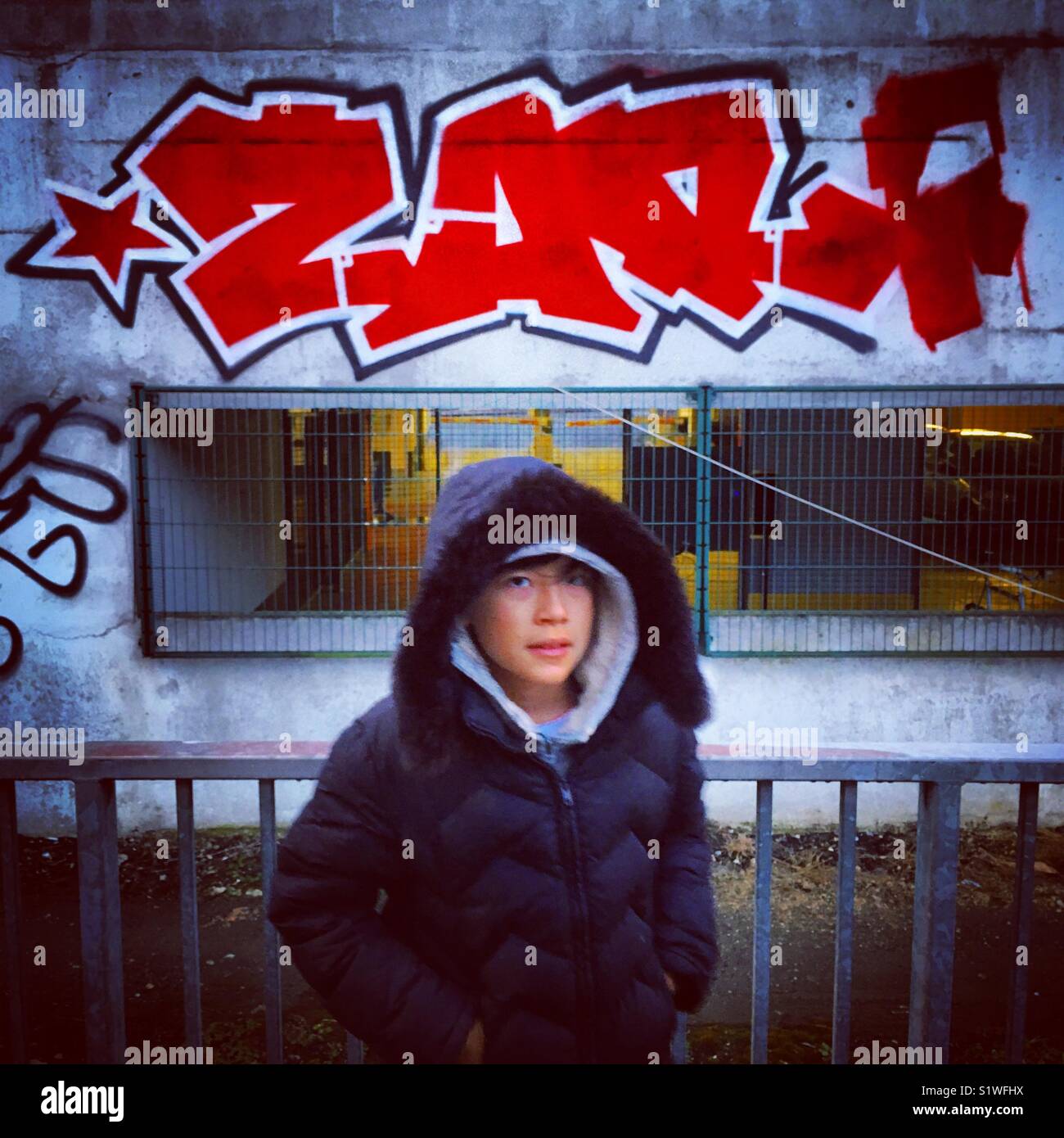 kid posing in front of a grafiti or tag in paris Stock Photo