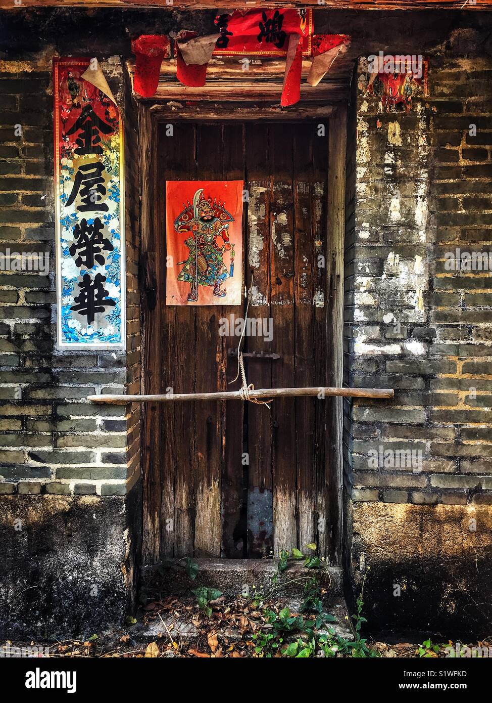 Derelict Chinese green brick house with paper banners and menshen (door gods), San Tau, Tung O Ancient Trail, Lantau Island, Hong Kong Stock Photo