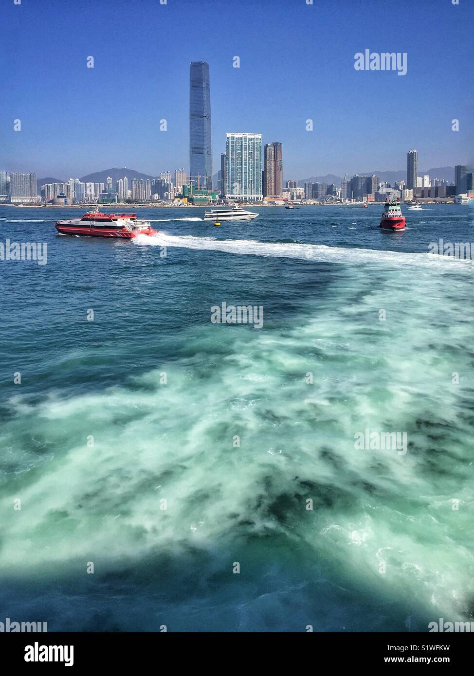 A Macau ferry leaves the terminal in Sheung Wan, with the ICC, Hong Kong’s tallest building, across Victoria Harbour in West Kowloon - Smartphone Captured Stock Image