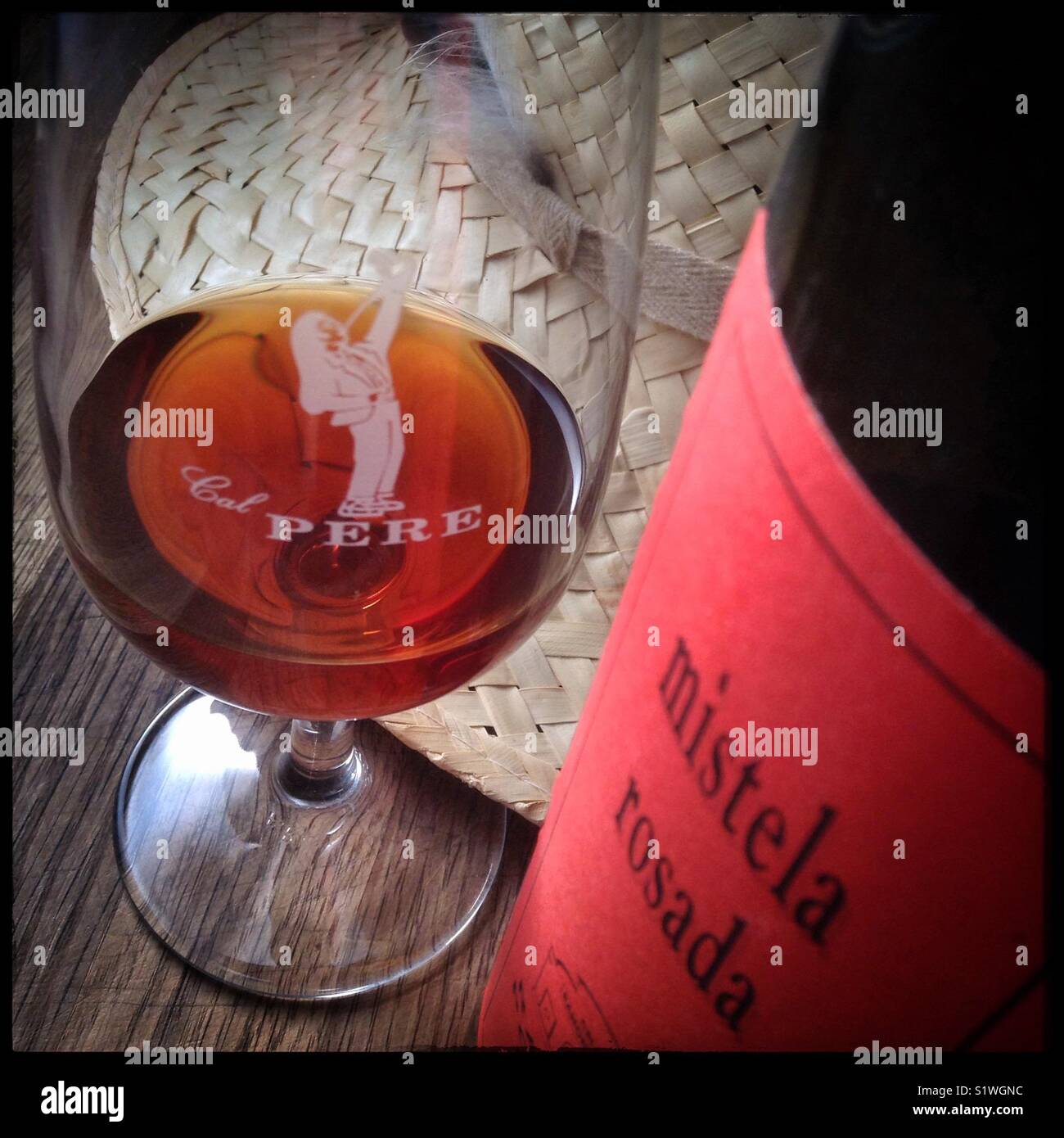 A glass of Mistela Rosada with bottle. Mistela is a local, traditional sweet fortified grape liquor made from maceration without fermentation. - Smartphone Captured Stock Image