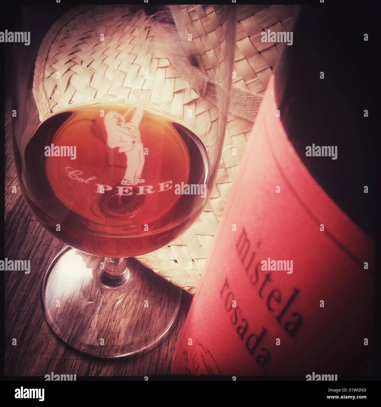 A glass of Mistela Rosada with bottle. Mistela is a local, traditional sweet fortified grape liquor made from maceration without fermentation. - Smartphone Captured Stock Image