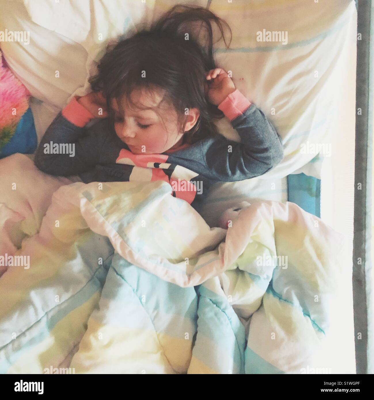 2 year old toddler girl napping in twin bed with safety rail Stock