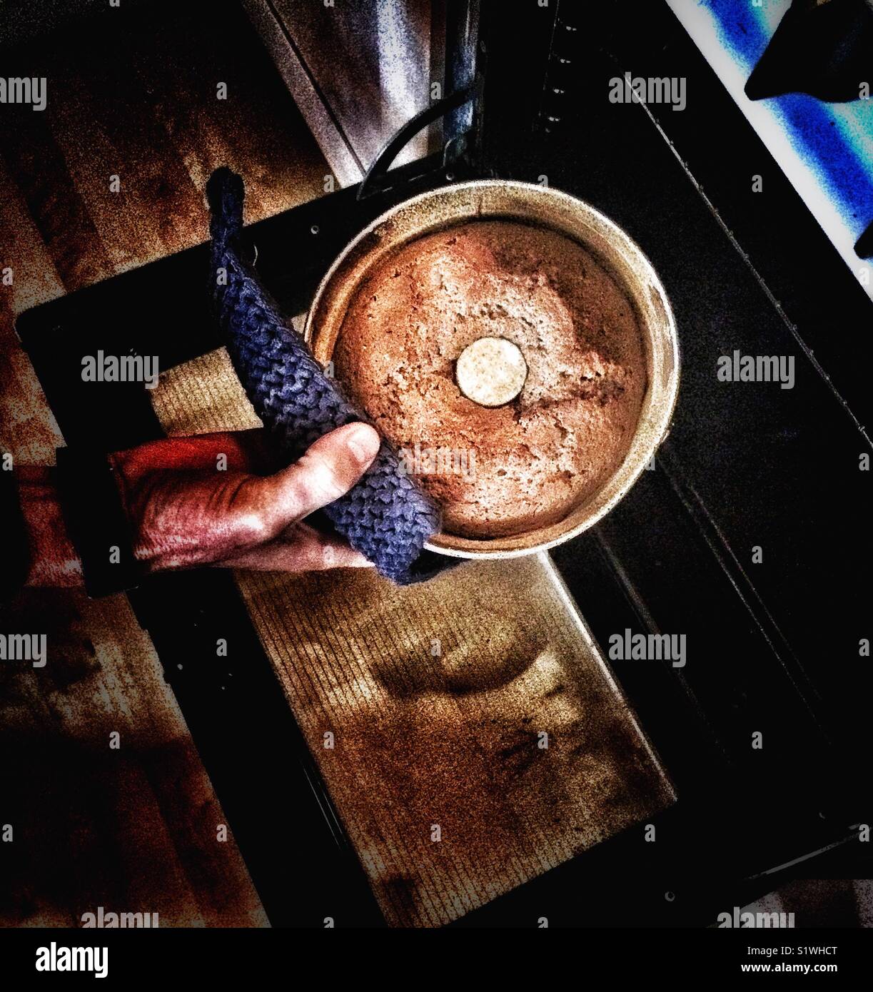 Mans hand removing circular homemade Swedish ginger cake from the oven - Smartphone Captured Stock Image