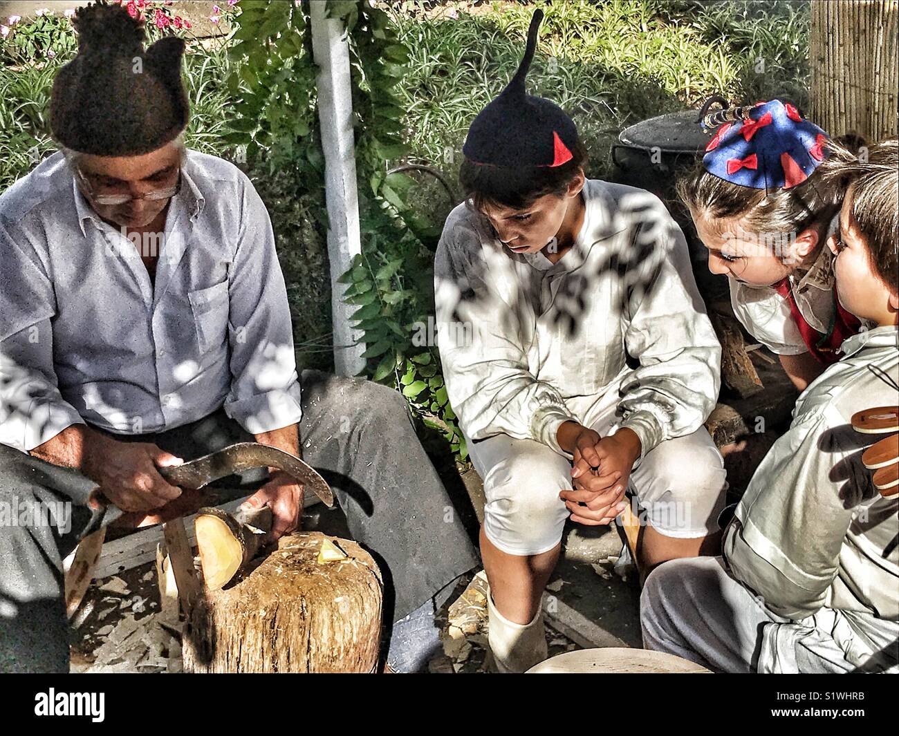 Children watching a craftsman carving wood at the Christmas Market, Funchal, Madeira, Portugal - Smartphone Captured Stock Image