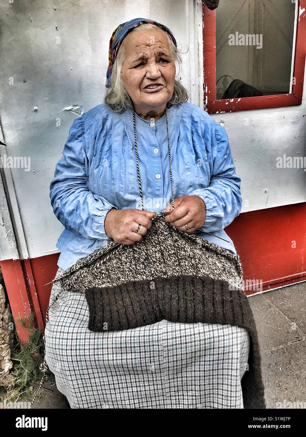 Senior Madeiran woman demonstrating knitting skills at the Christmas Market in Funchal, Madeira, Portugal. - Smartphone Captured Stock Image