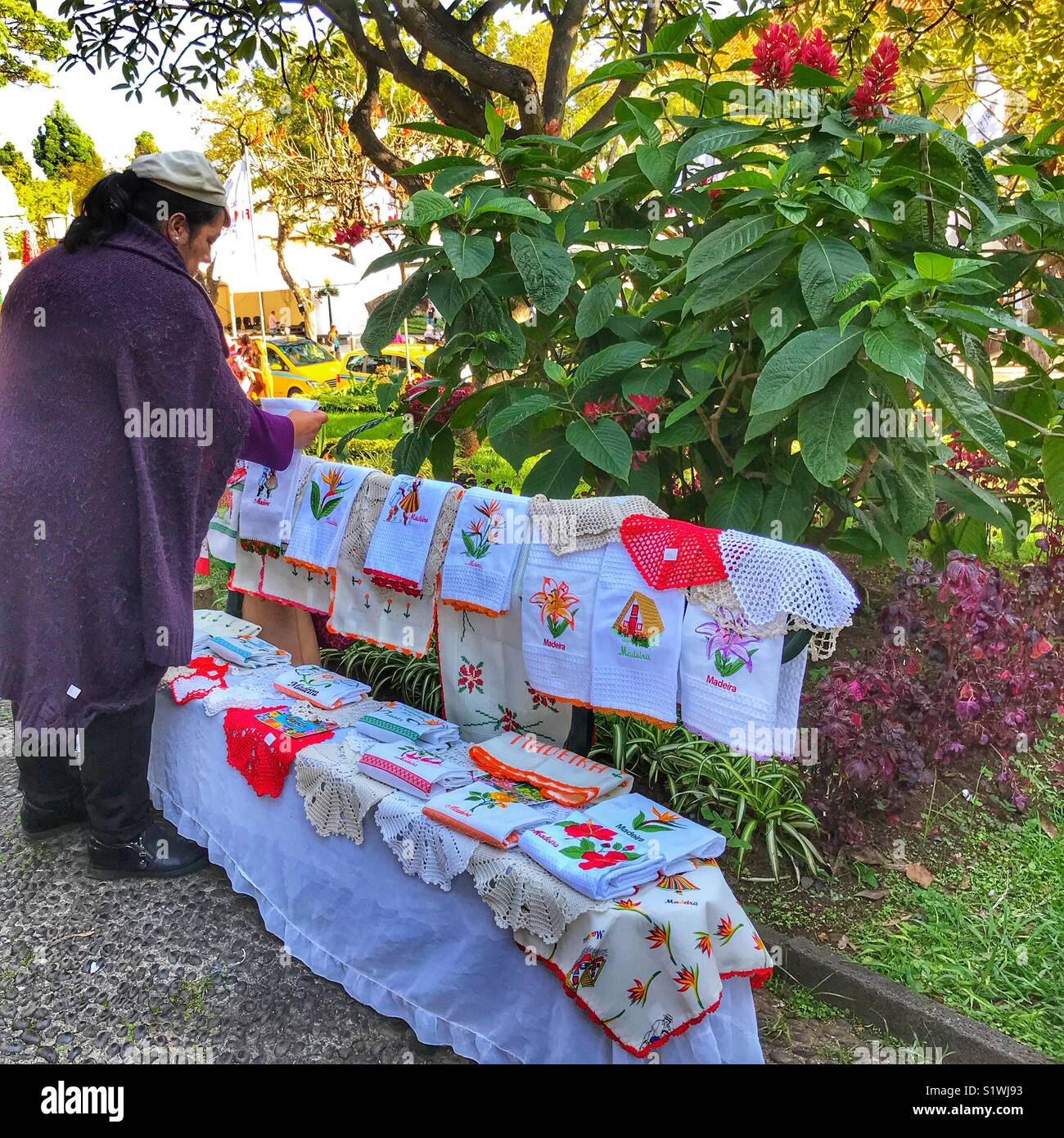 Woman selling handmade Madeiran lace from a bench in the Municipal Gardens at Christmas time. Funchal, Madeira, Portugal - Smartphone Captured Stock Image