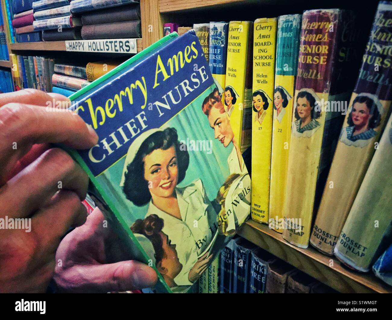 Hands holding vintage book  Cherry Ames Chief Nurse by Helen Wells in the World Largest Bookstore in Tacoma, Washington state - Smartphone Captured Stock Image