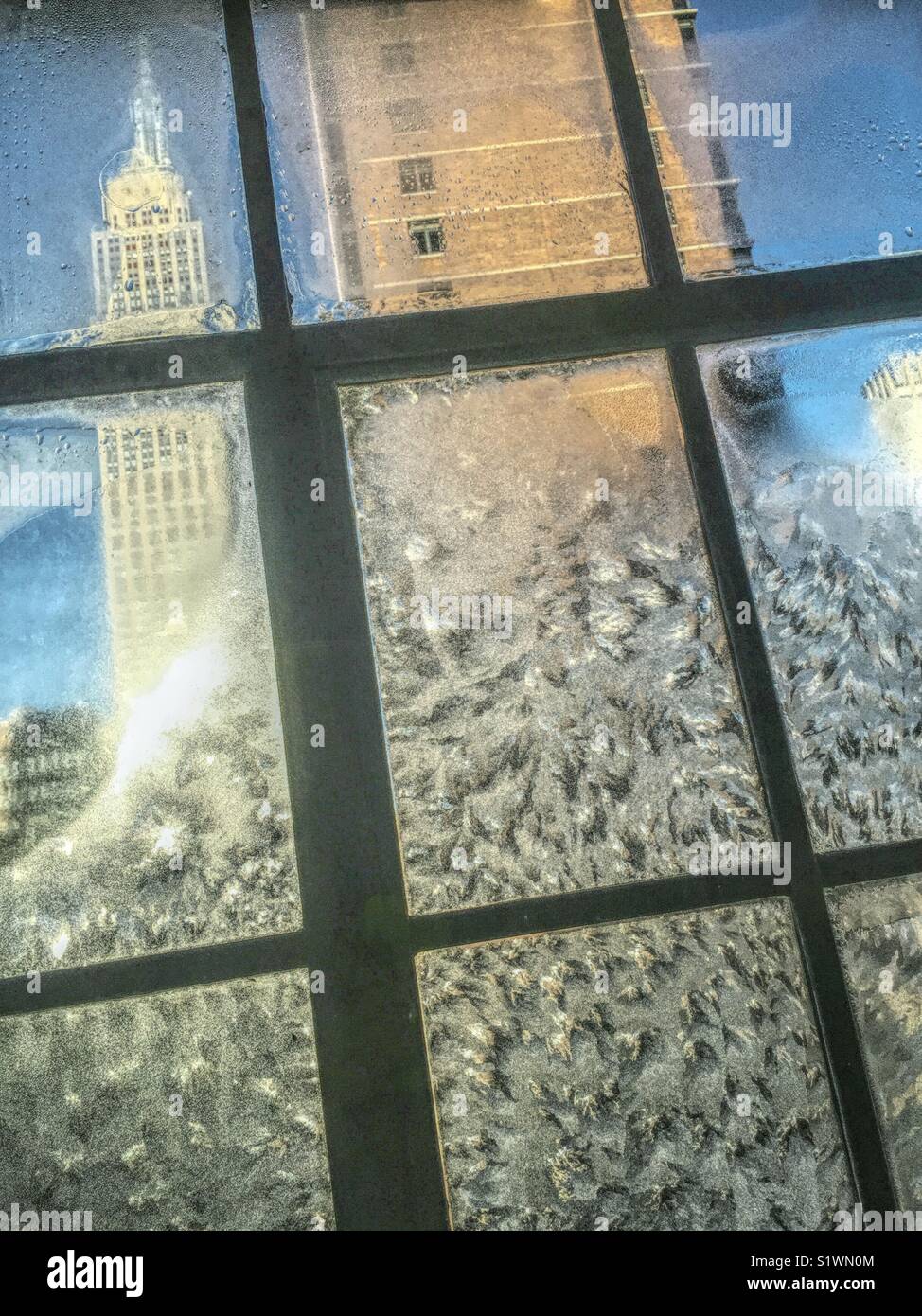 View of the Empire State building through glass casement window encrusted with ice during winter storm, NYC, USA - Smartphone Captured Stock Image
