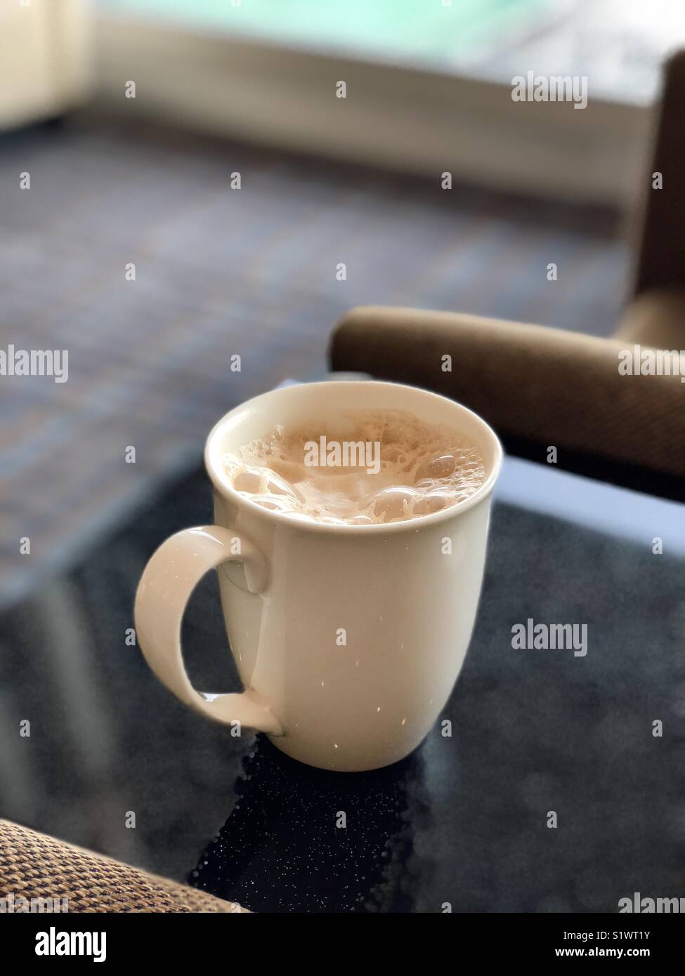Cup of hot drink with froth on top of marble table shot in portrait - Smartphone Captured Stock Image