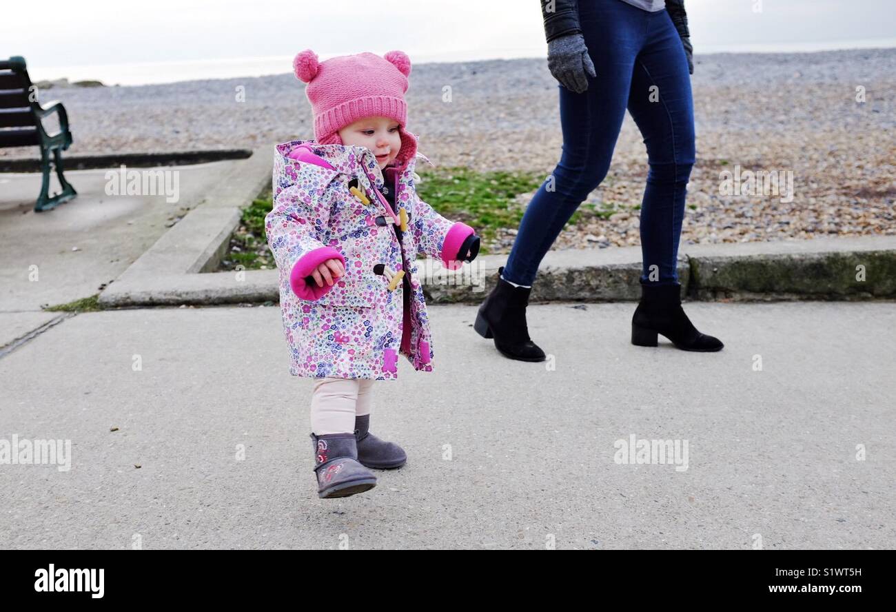 Young 14 month old baby taking first steps learning to walk toddler Stock Photo