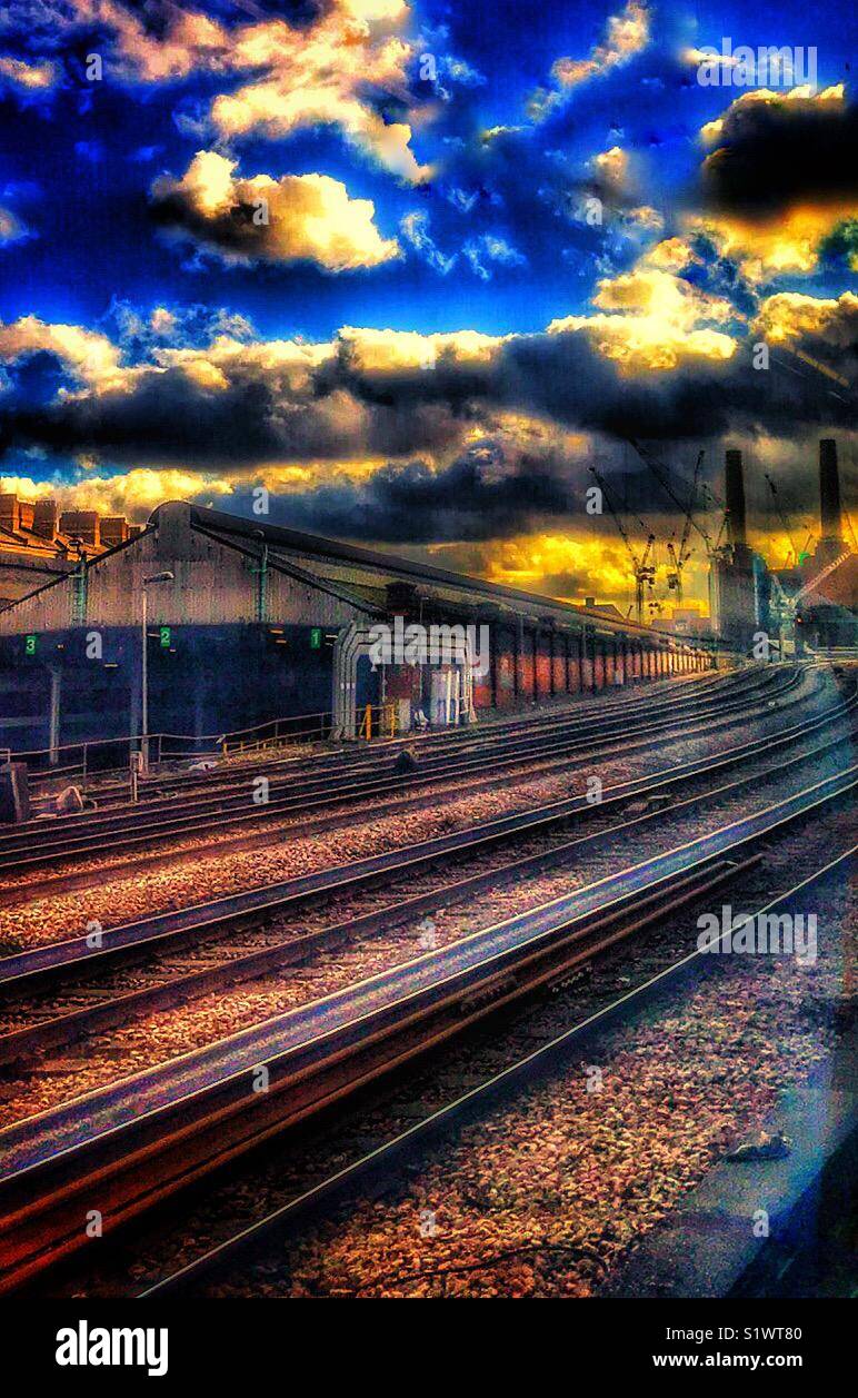 A view from London’s Victoria Station of railway track with train sheds on the left and iconic Battersea Power Station on the horizon - Smartphone Captured Stock Image