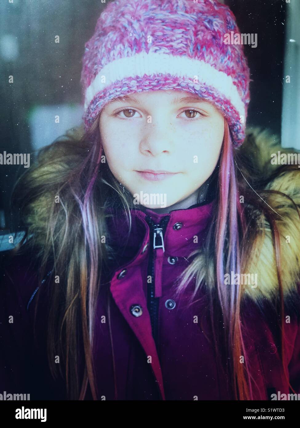 Portrait of a girl with dyed purple hair wearing winter parka and hat processed in cool tones - Smartphone Captured Stock Image