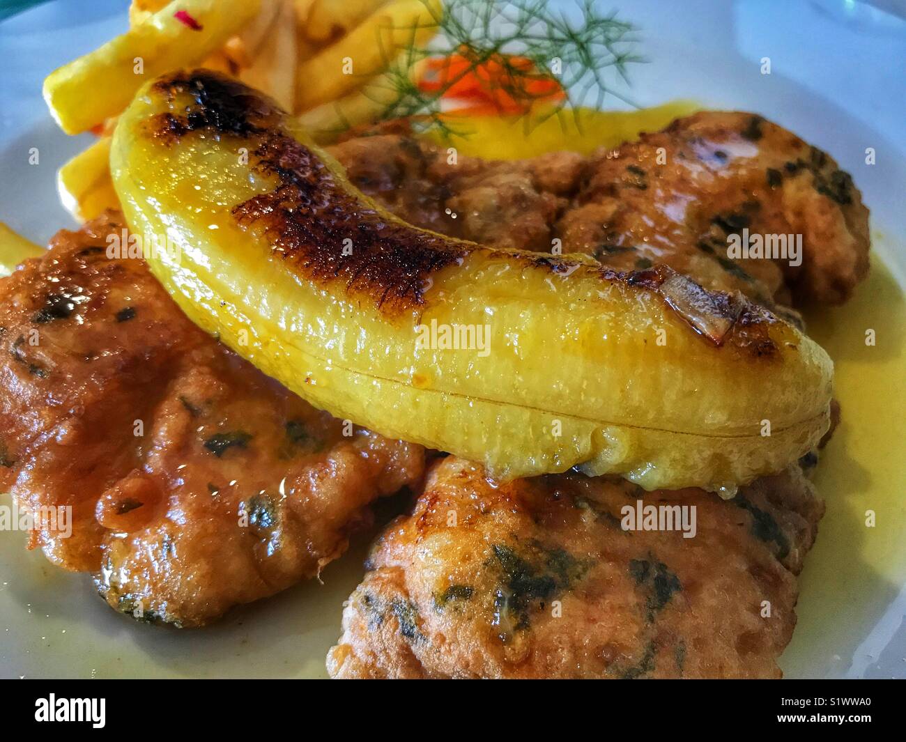 Scabbard fish with French fries, topped with a fried banana. A typical dish from Madeira, Portugal Stock Photo