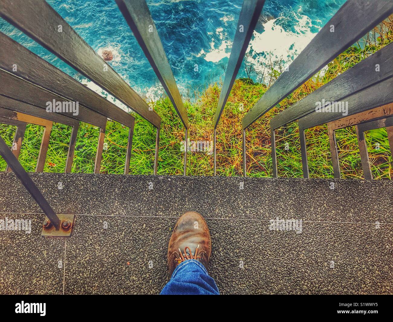POV Looking over iron railings down a cliff to rough sea, waves and rocks below, Madeira, Portugal Stock Photo