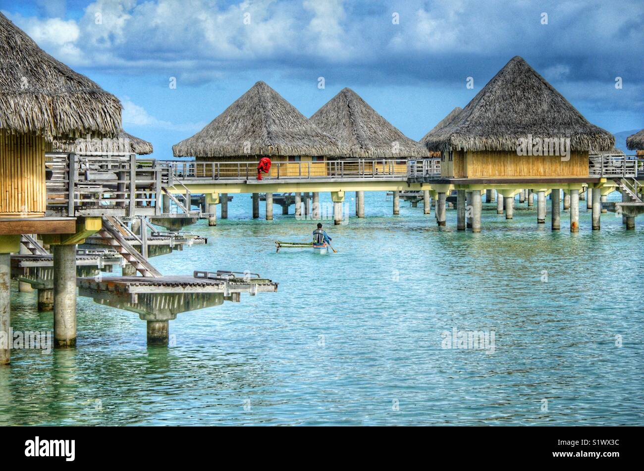 Out rigger canoe paddling around the bungalows on the island of Bora-Bora, French Polynesia in the South Pacific - Smartphone Captured Stock Image