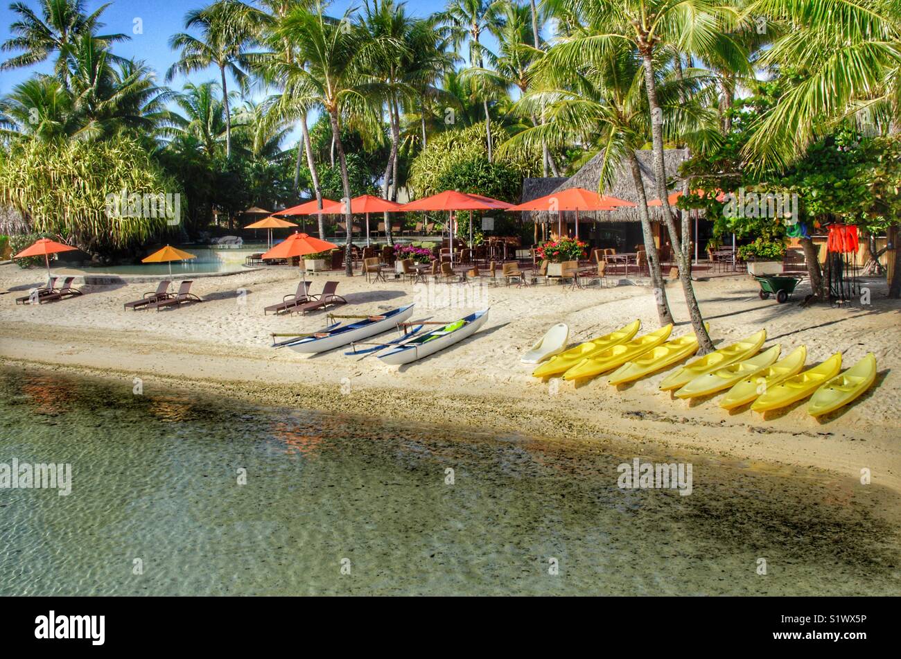 Exotically resort on the island of Bora-Bora French Polynesia in the South Pacific. Kayaks and out rigors align the beach waiting for patrons to go out onto the water in the lagoon. - Smartphone Captured Stock Image