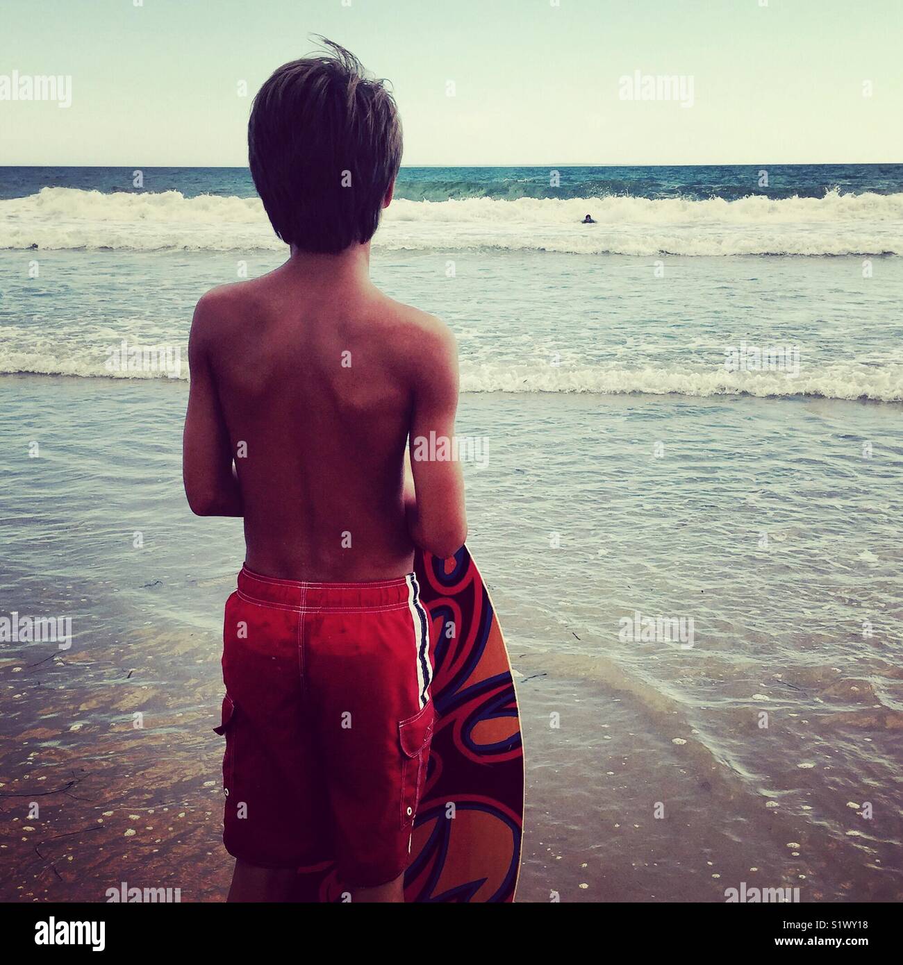 Boy waiting for perfect wave for skim boarding Stock Photo