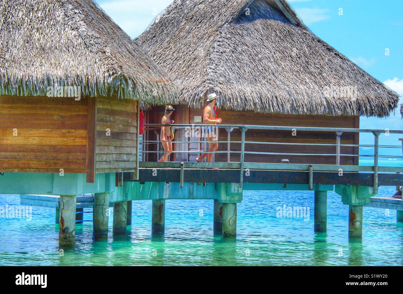 Couple leaving there over the water bungalow in the lagoon of Bora-Bora, French Polynesia Stock Photo