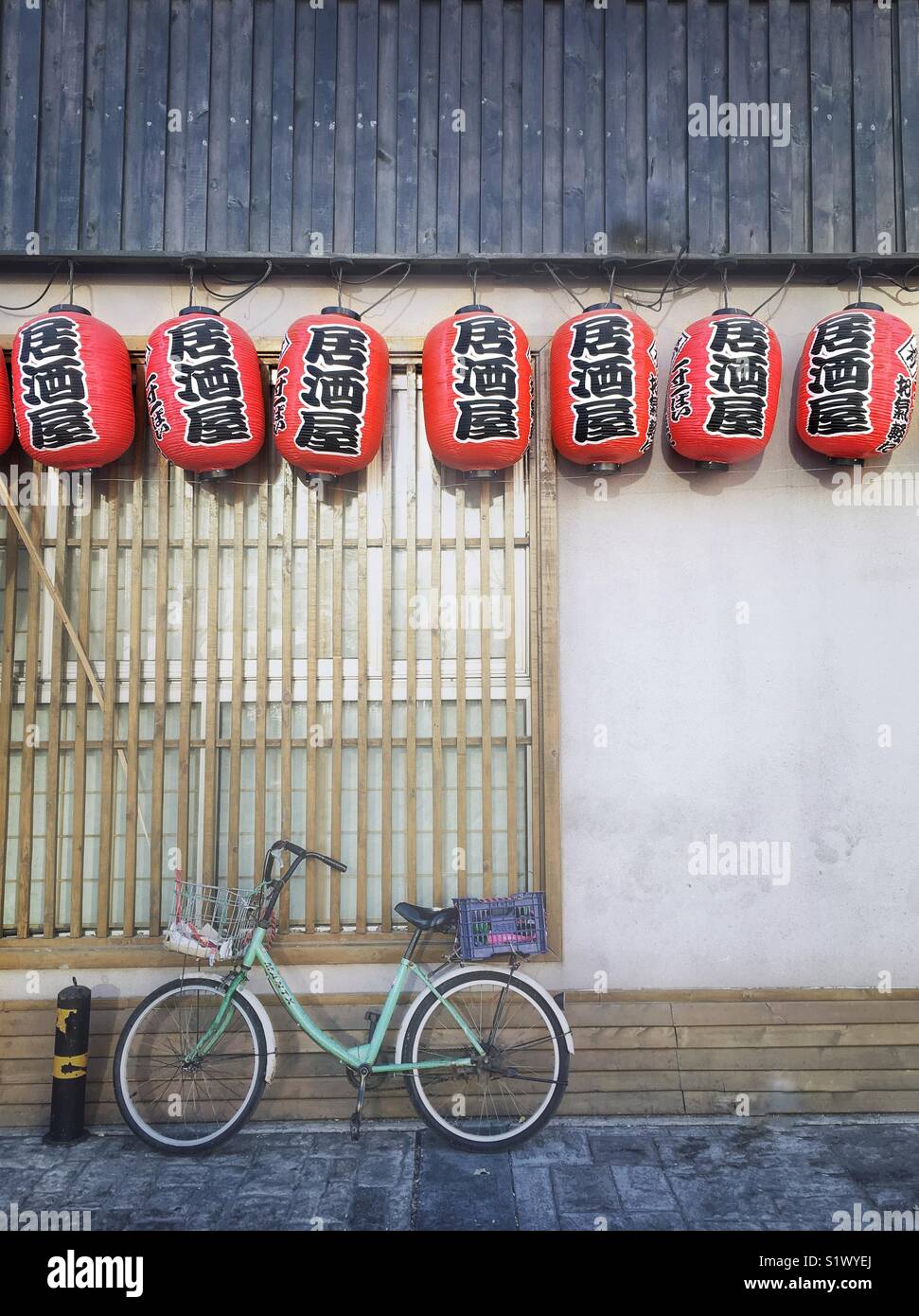 Chinese red lantern and a bicycle by the wall. Stock Photo