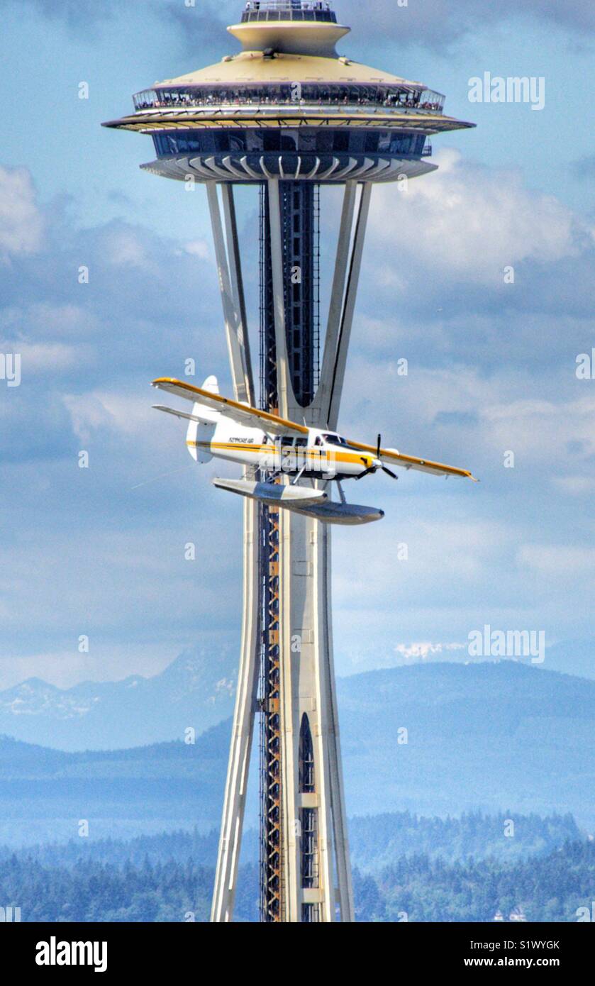 Sea plane from Kenmore Air passing right in front of the space needle at a low altitude as it is getting ready to land at Lake Union in Seattle Washington - Smartphone Captured Stock Image