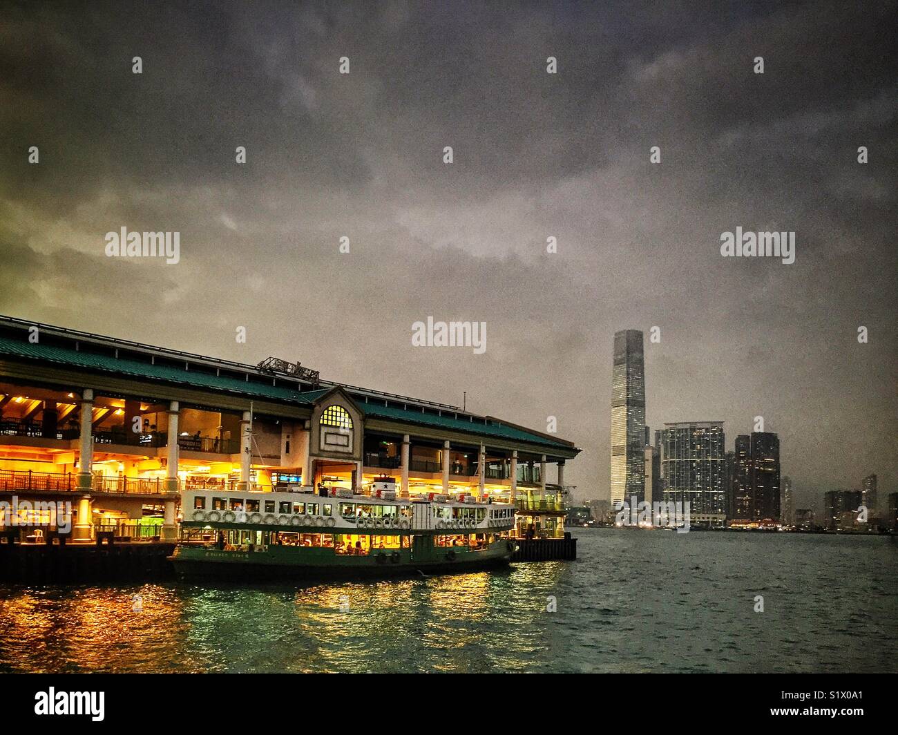 A Star Ferry at Central Pier 7 at dusk, with the ICC, Hong Kong’s tallest building, across Victoria Harbour in West Kowloon - Smartphone Captured Stock Image