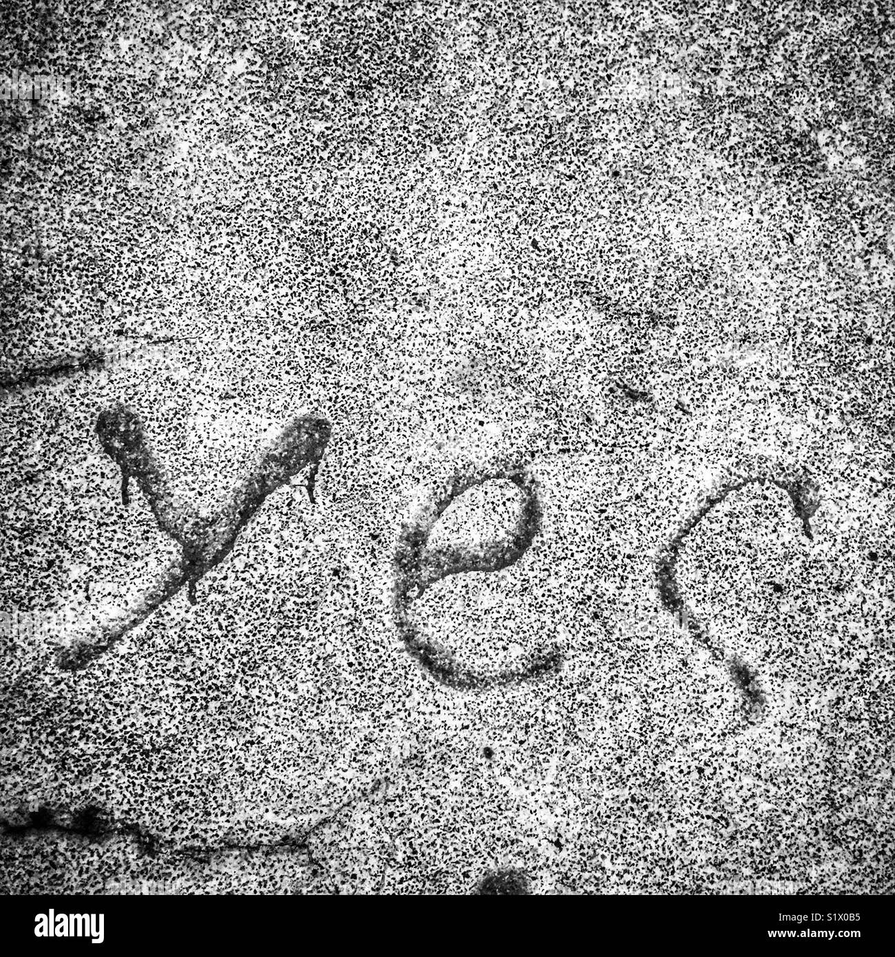 ‘Yes’ - faded graffiti on a stone wall in Happy Valley, Hong Kong (monochrome version) - Smartphone Captured Stock Image