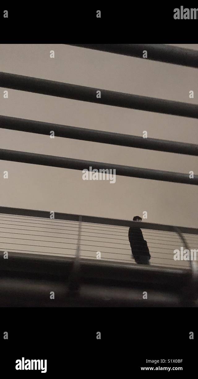 Man passing by metal bars of a bridge in London UK - Smartphone Captured Stock Image