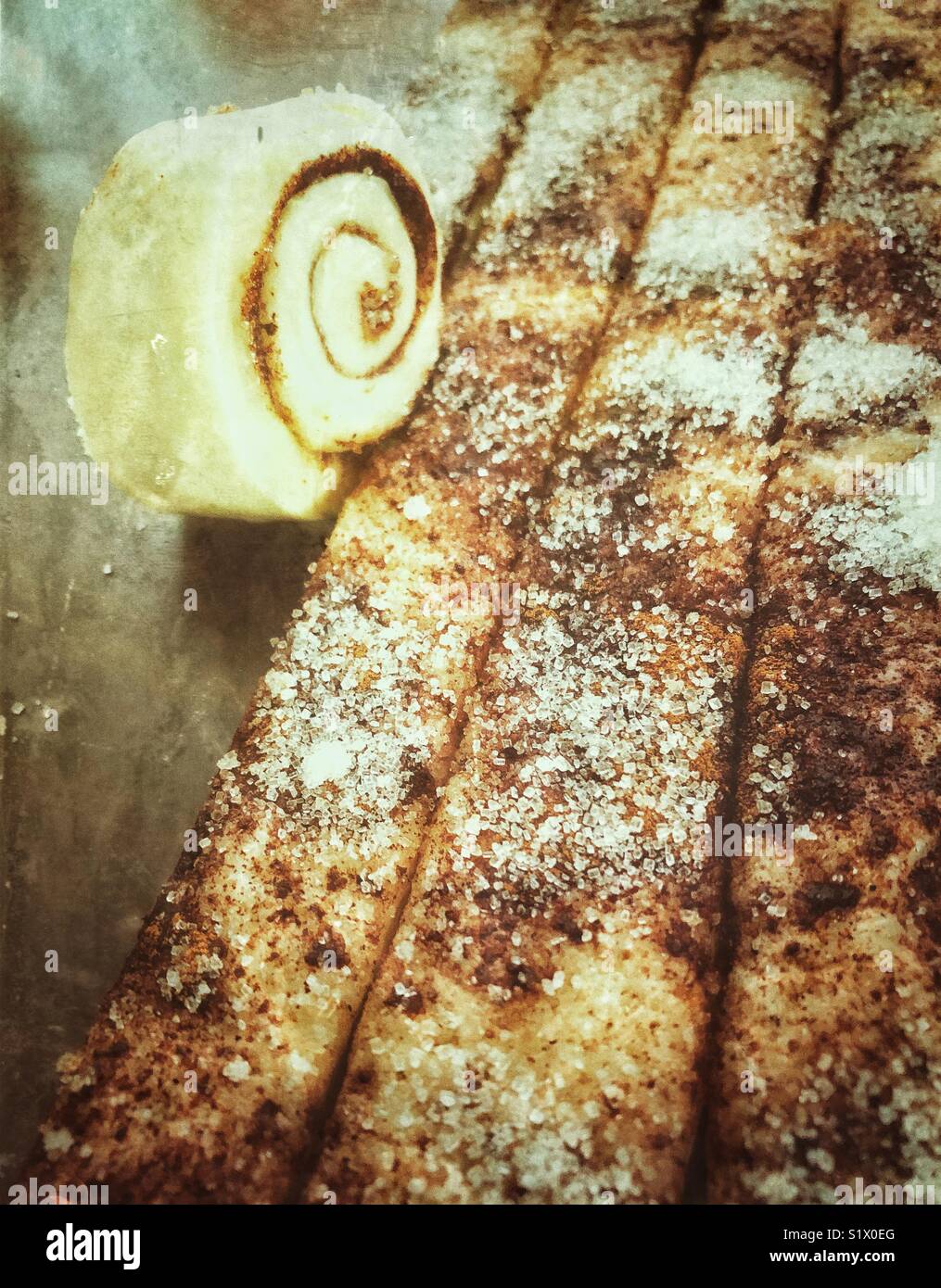 Rolling strips of dough covered in cinnamon and sugar to make cinnamon rolls - Smartphone Captured Stock Image