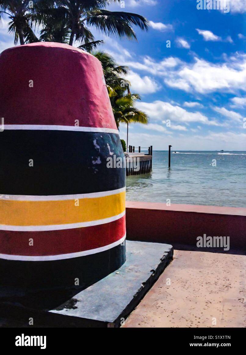 Iconic buoy at the southernmost point in Key West, Florida, USA, with palm trees, sky and ocean in the background Stock Photo