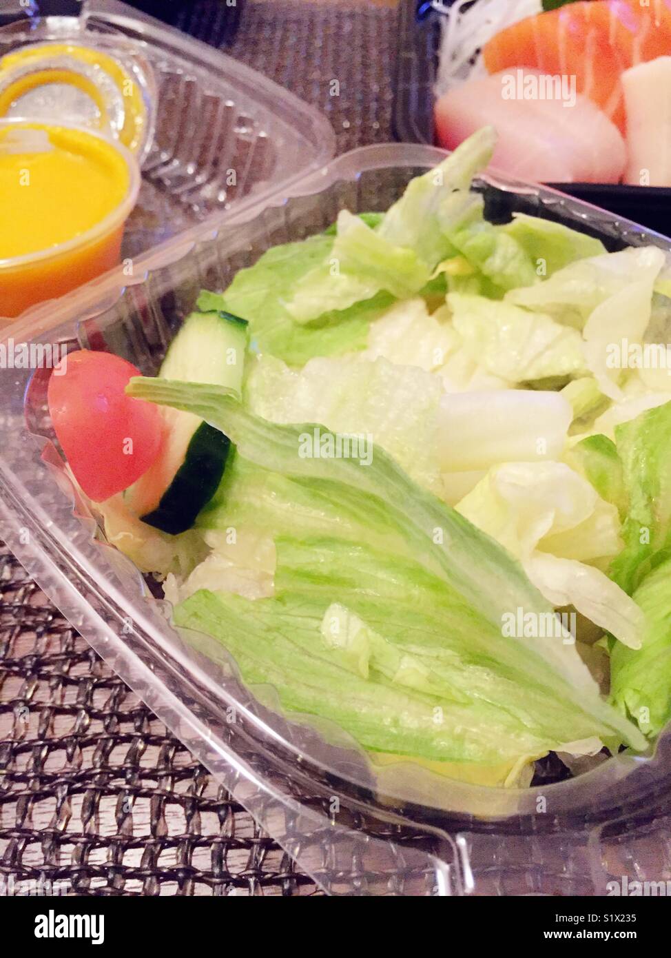 Plastic containers of salad and sushi from Japanese take out restaurant