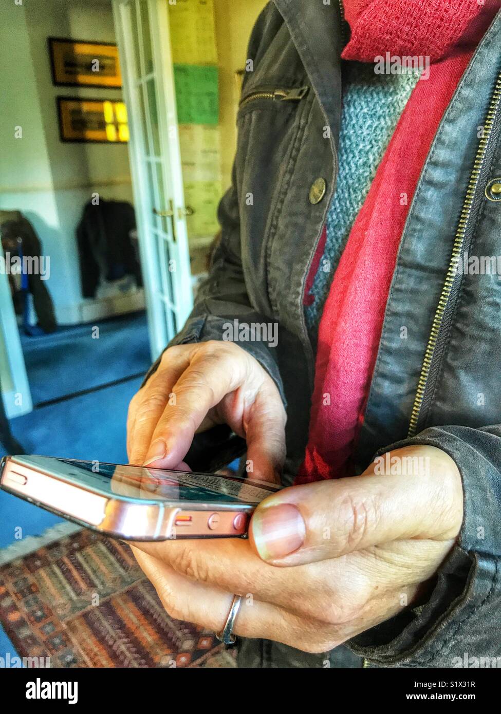 Woman using smartphone, indoors, close-up, midsection - Smartphone Captured Stock Image