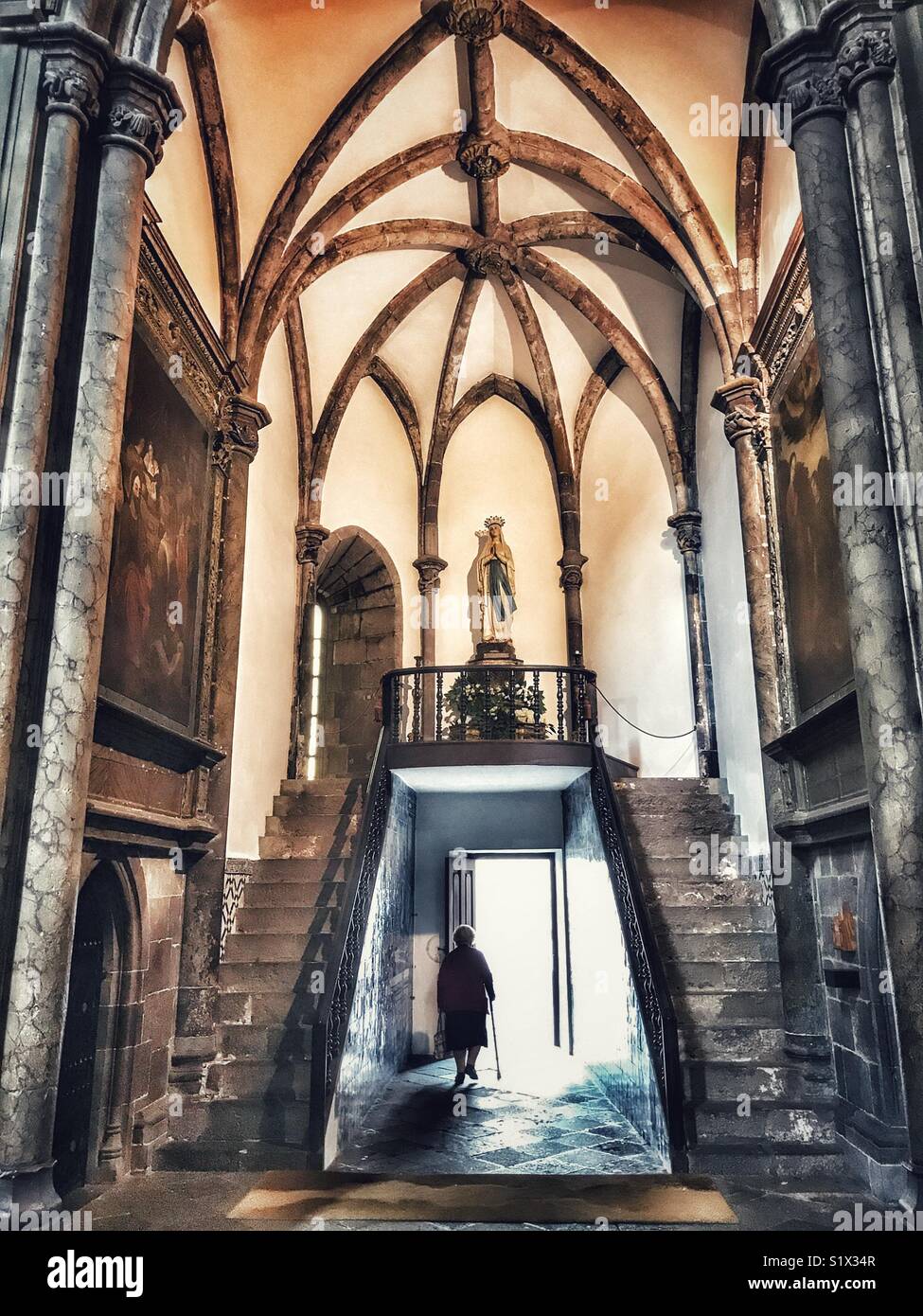 Silhouette of an old lady with a walking stick leaving the Cathedral Se by a vaulted side entrance, Funchal, Madeira, Portugal - Smartphone Captured Stock Image