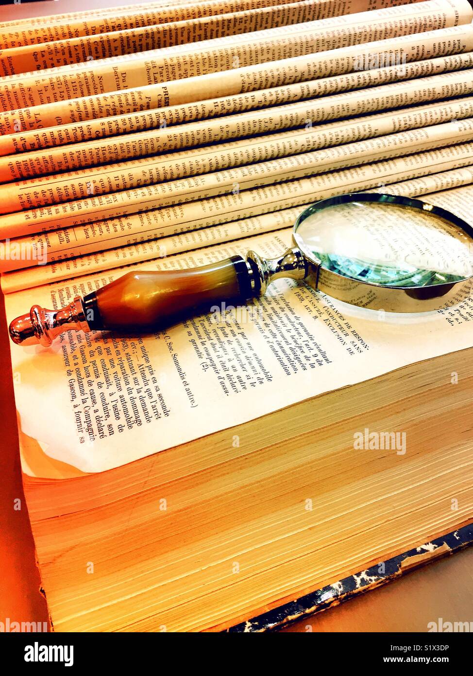 Hardback book with turn the pages has a magnifying glass on it - Smartphone Captured Stock Image