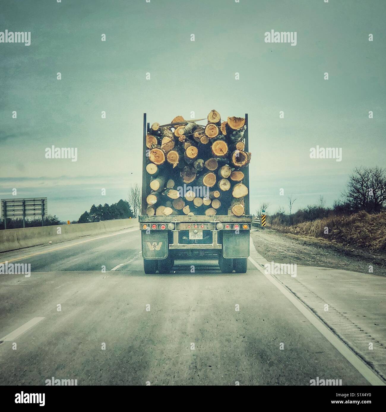 Logging truck on two lane highway as seen from point of view of person driving behind - Smartphone Captured Stock Image
