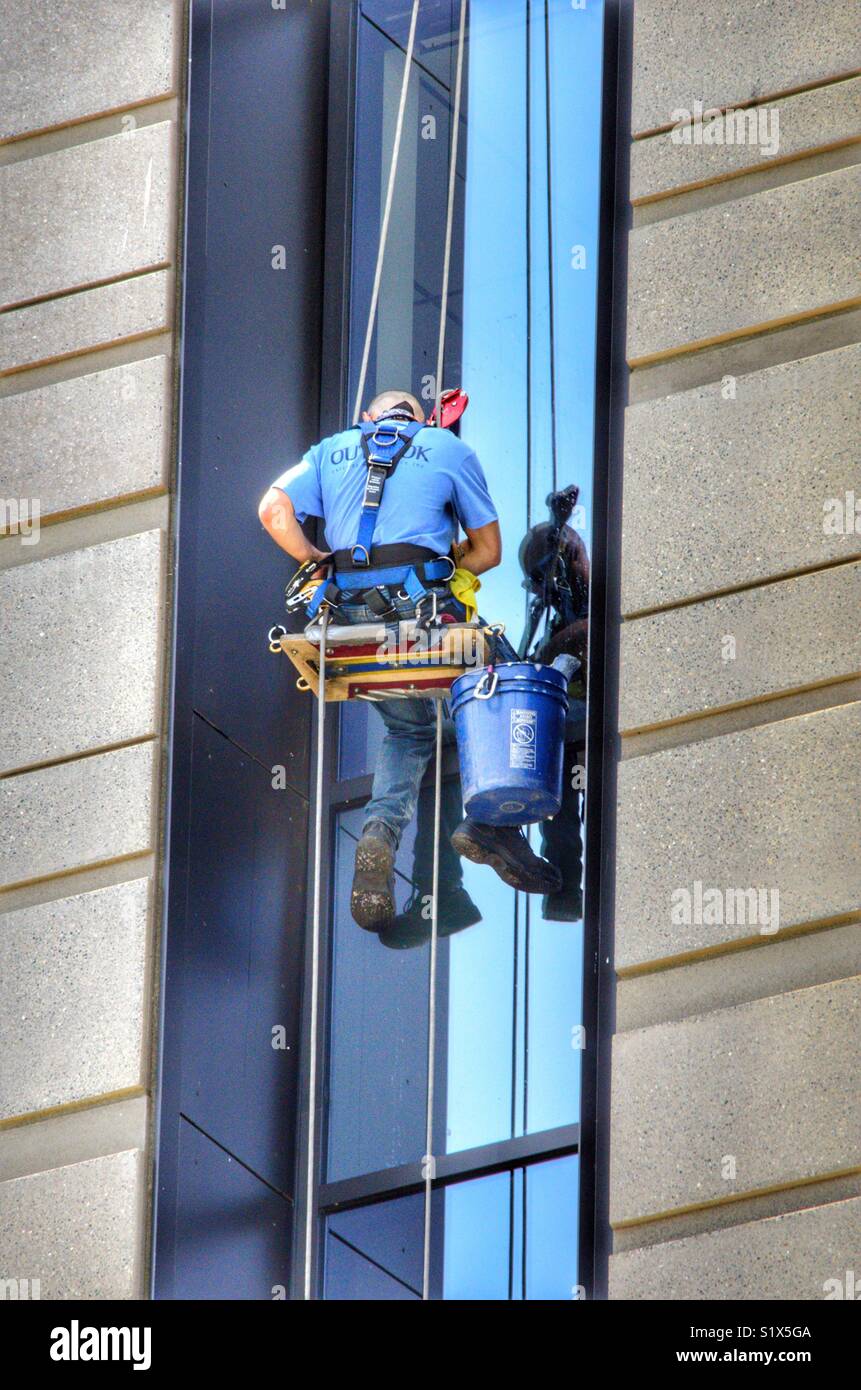 Window washer hanging from the ropes off the side of a building in Seattle Washington Stock Photo