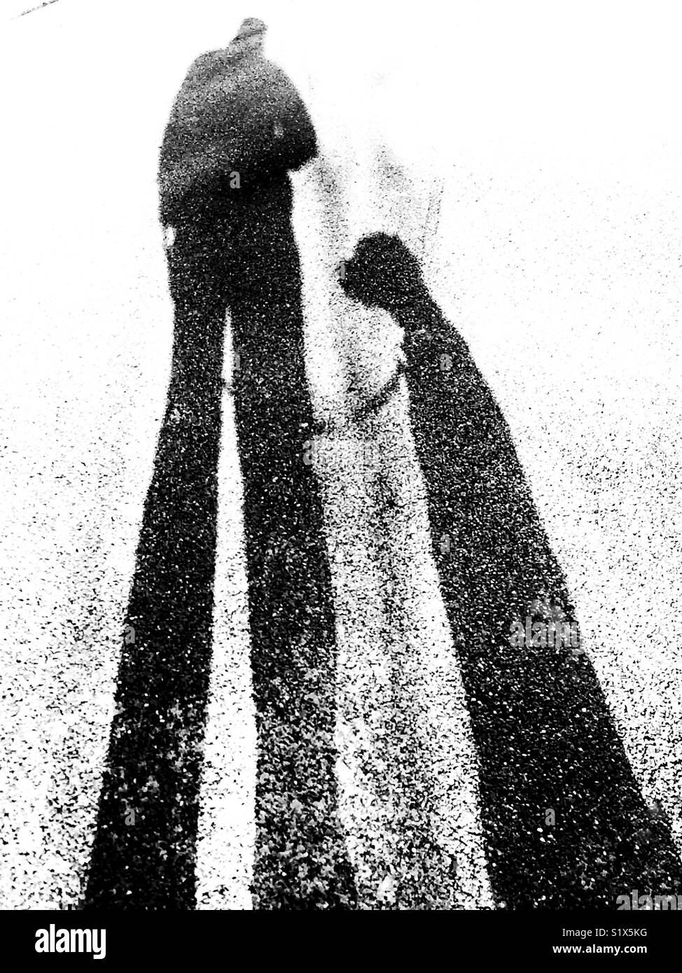 The dark shadows of a man and his pet dog sitting obediently by his side - Smartphone Captured Stock Image