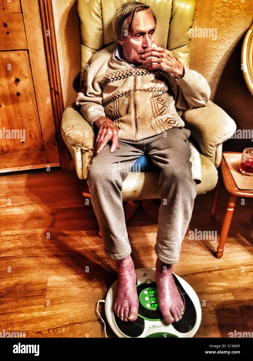 Elderly man with poor circulation having an electronic foot massage Stock Photo